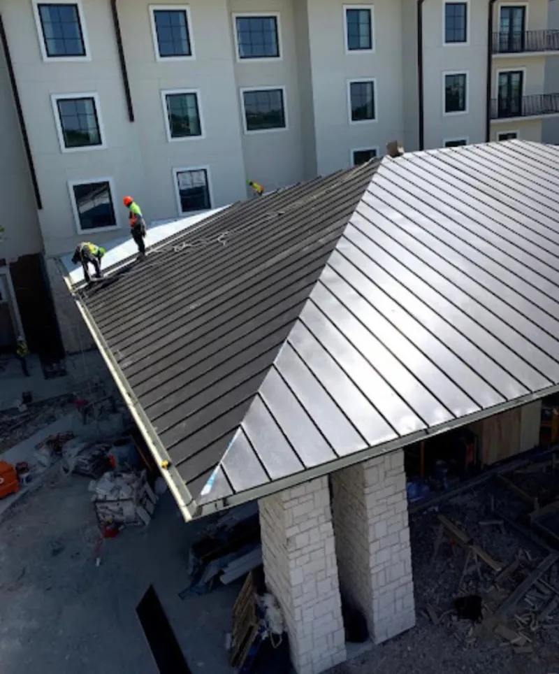 Crew installing standing seam metal roof panels on a commercial project in Huntertown